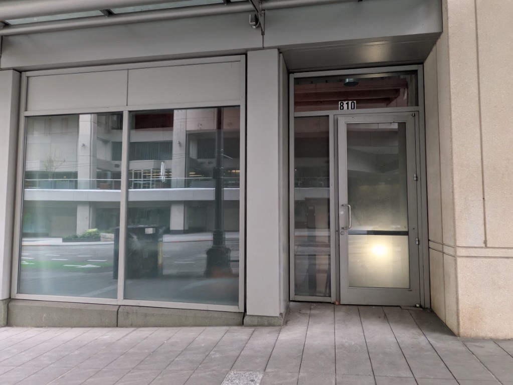 810 Pike Street. The address is the only marking on the door. Behind it, propped open with a wedge — construction, May 6, 2026.